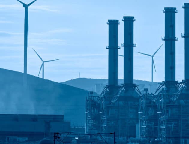 chimneys with wind turbines in the background